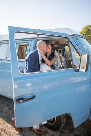 A romantic moment captured in a vintage blue van with mountains in the background.