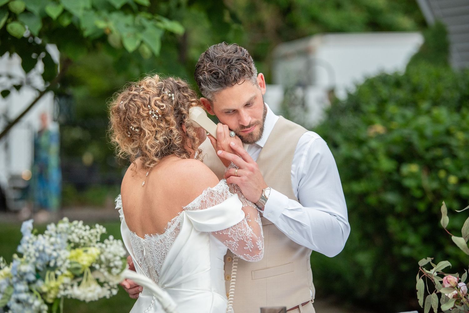Wedding couple sharing intimate moment in lush garden setting with white flowers.