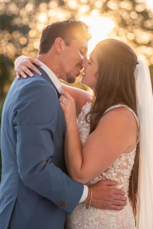 A sunset wedding portrait with golden bokeh lighting and intimate embrace.
