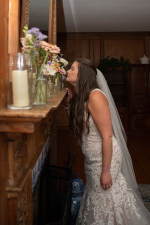 A bride in an elegant lace gown and veil poses in a rustic wooden interior.