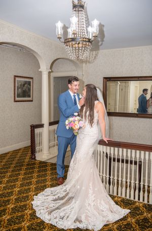 A romantic wedding moment captured in an elegant interior with crystal chandelier and patterned carpet.