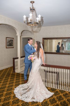 A couple shares an intimate moment in a vintage interior with ornate carpet and crystal lighting.