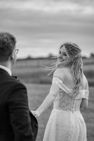 A black and white candid moment with wind-swept hair against a moody sky.