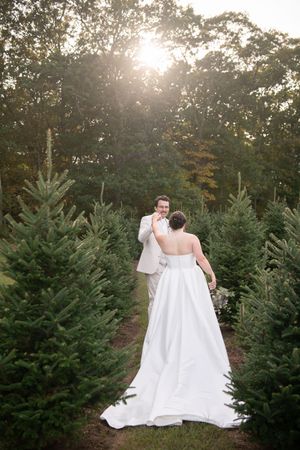 A sunset wedding portrait among evergreen trees with dramatic backlighting.