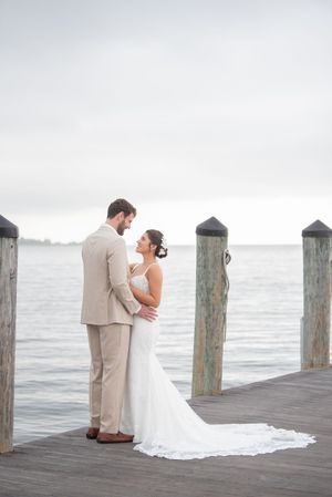 A romantic moment captured on a wooden pier overlooking the water with mooring posts in the background.