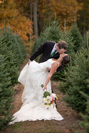A dramatic dip pose between evergreen trees with a beautiful bouquet.
