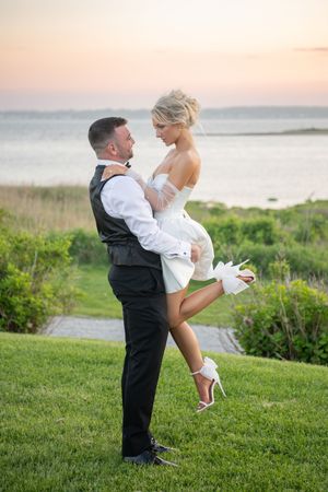 Playful sunset wedding photos on a grassy oceanfront hill showing joyful moments between the couple.