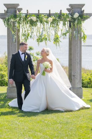 A romantic wedding photo series under a garden pergola with flowing white dress and greenery overhead.