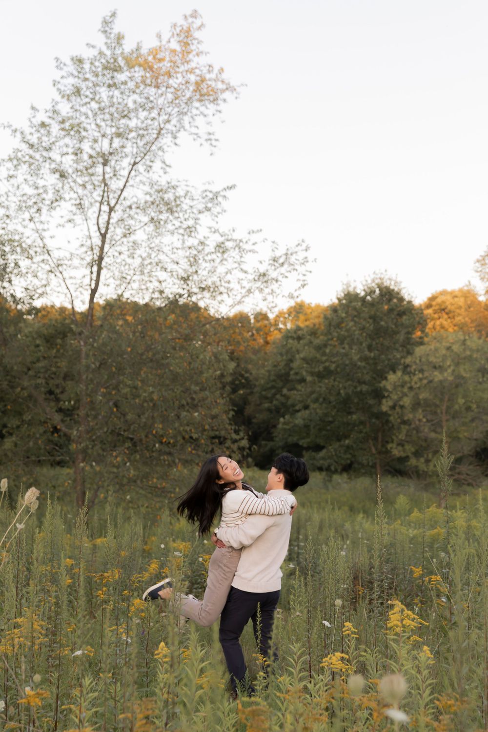 couple spinning around in a field of wildflowers at Addison oaks county park