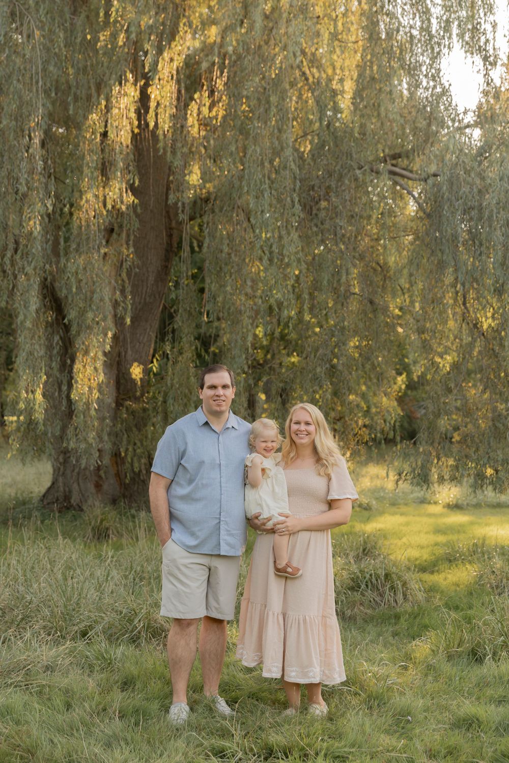 family posing for a photo in front of a willow tree at Addison oaks county park