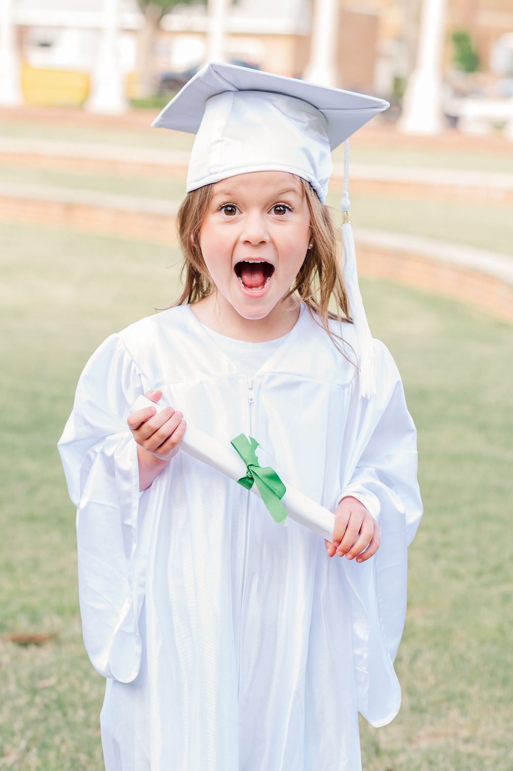 Kindergarten graduate in white cap and gown with diploma, Newnan, GA