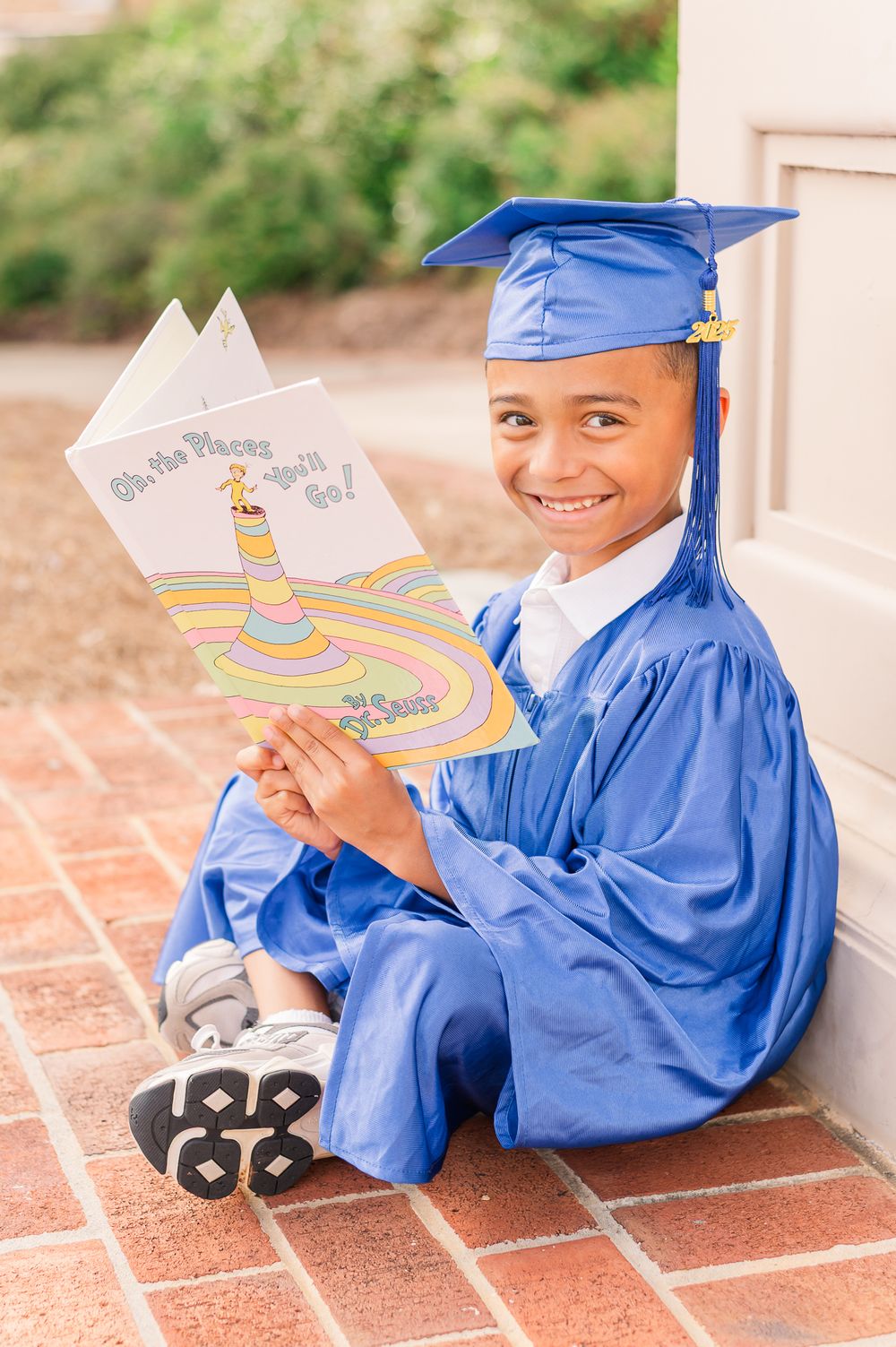 Kindergarten grad in blue cap and gown reading, Newnan, GA