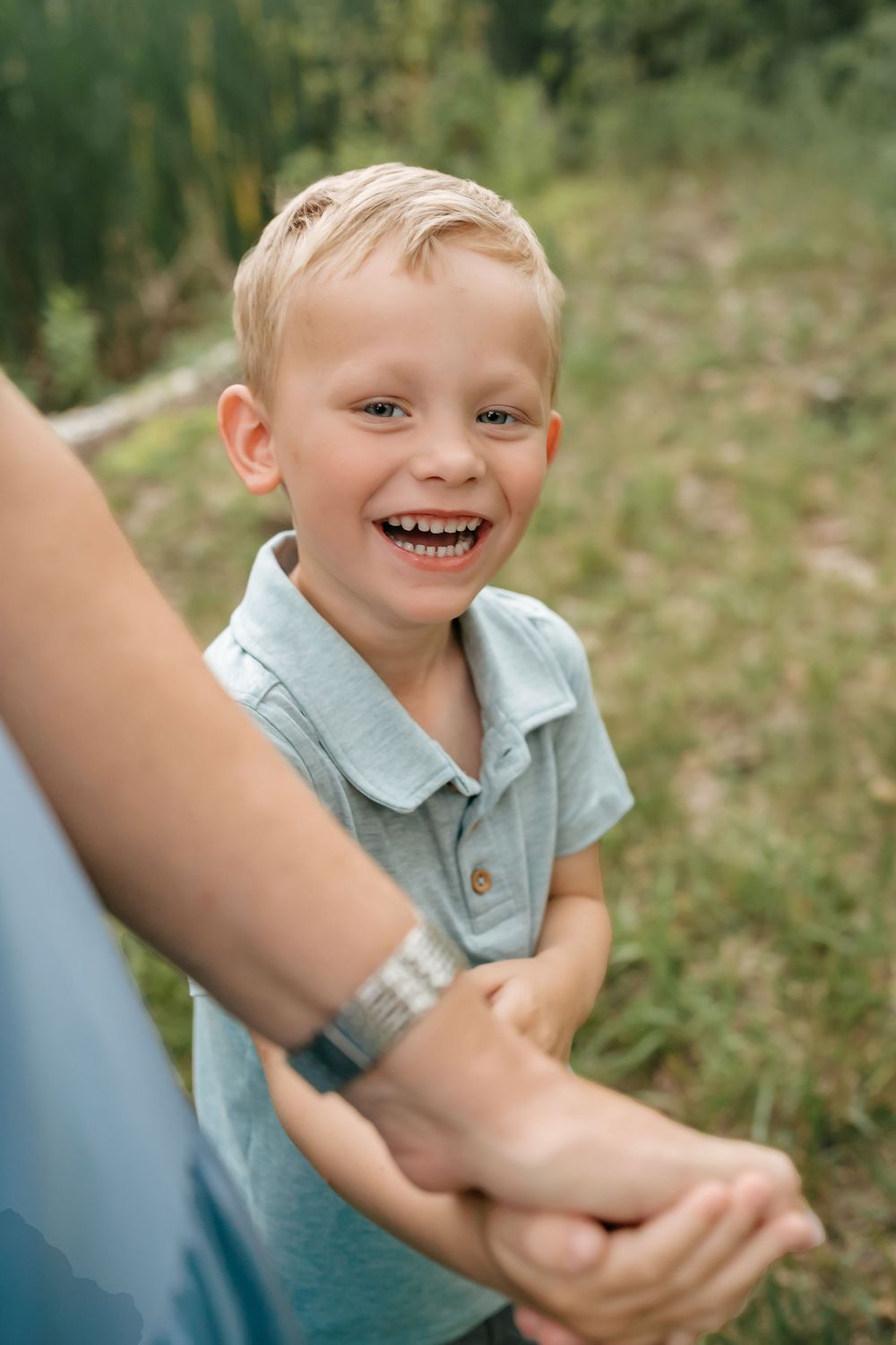 A series of five sequential photos showing playful moments of a young child in a light blue shirt outdoors.