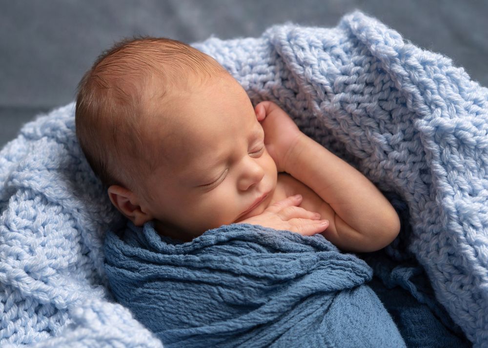 Newborn little boy in blue at Cherished Moments Photography.