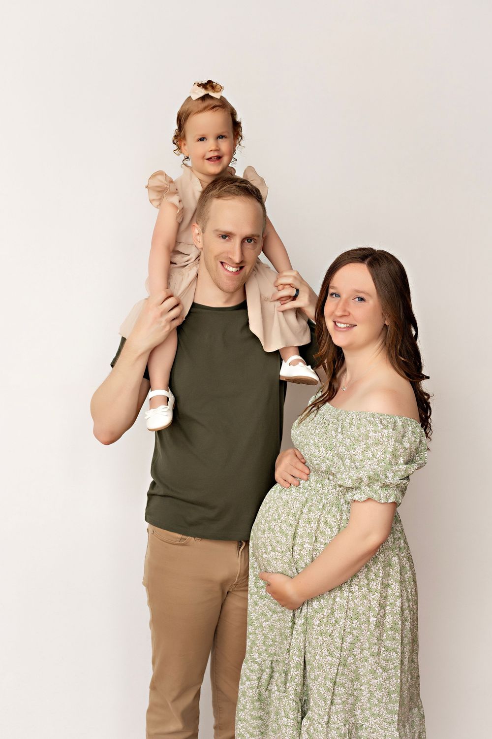 A family poses together in a modern studio setting wearing coordinated casual outfits.  Kendall Kuss Photography Watertown WI