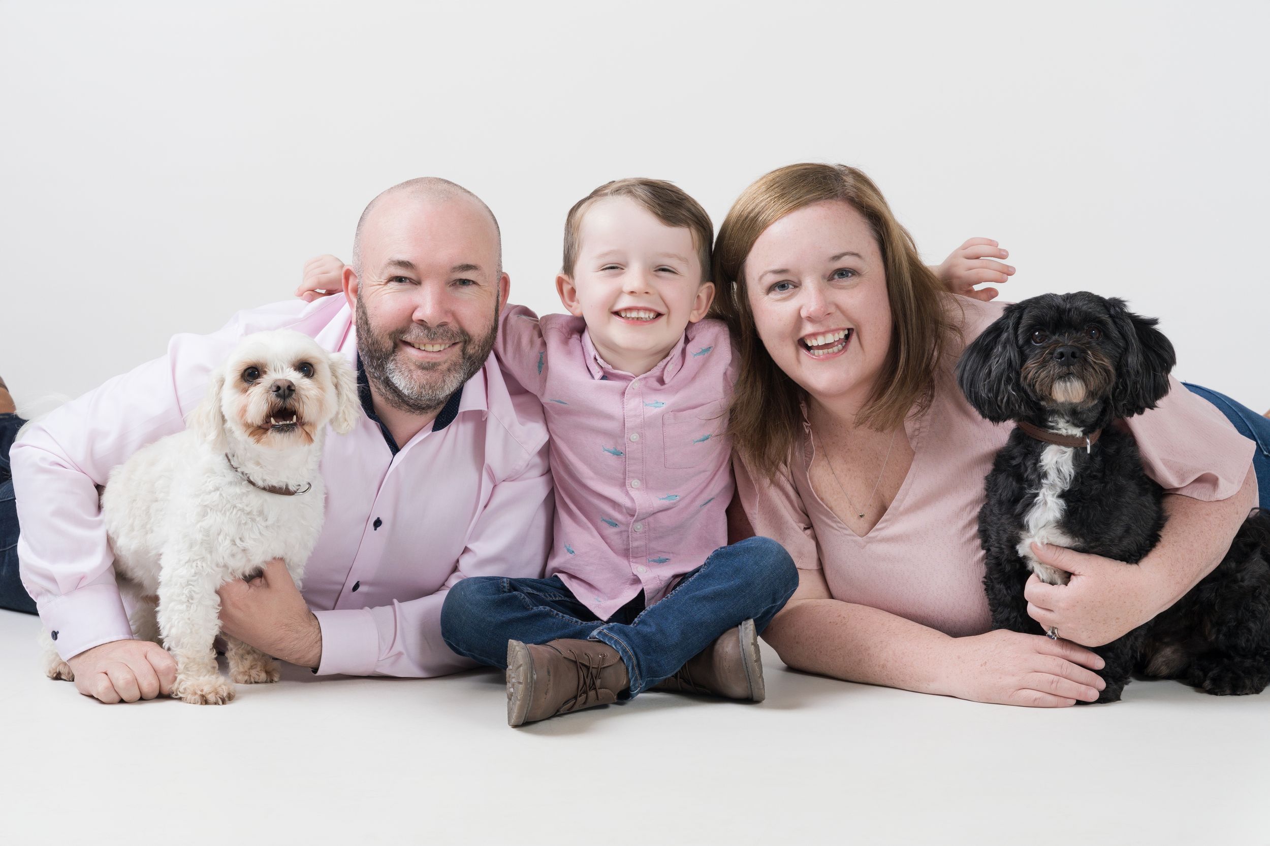 Family portrait with two dogs sitting together on white background.