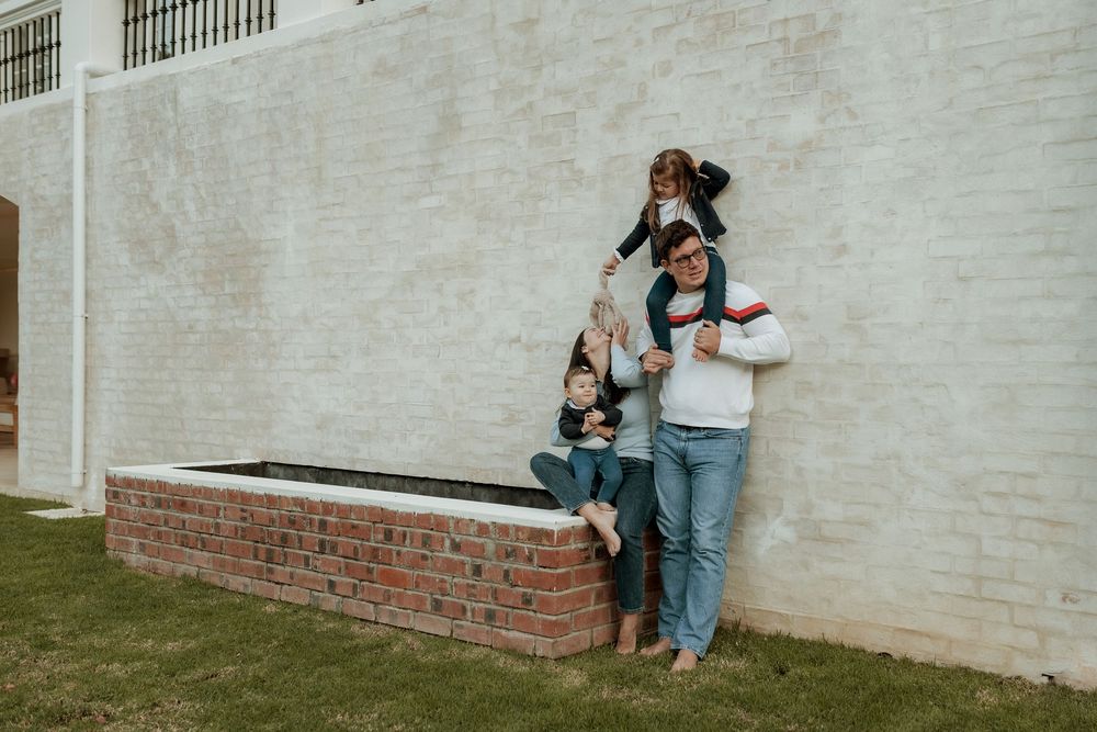A series of four connected urban engagement photos showing a couple posing against white brick walls.