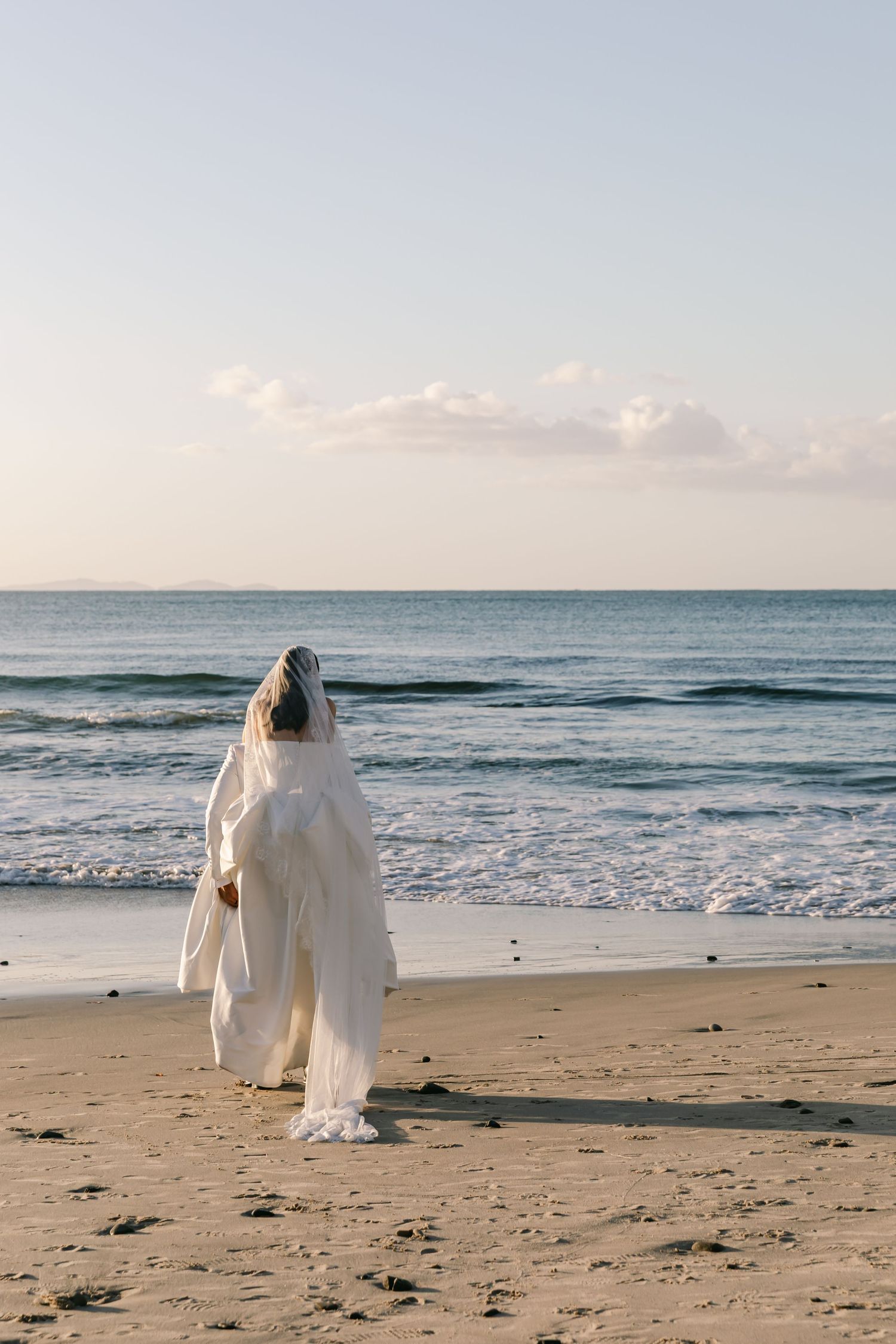Couple in wedding attire walking along a boat harbour. Sunset wedding near ocean in Sydney.