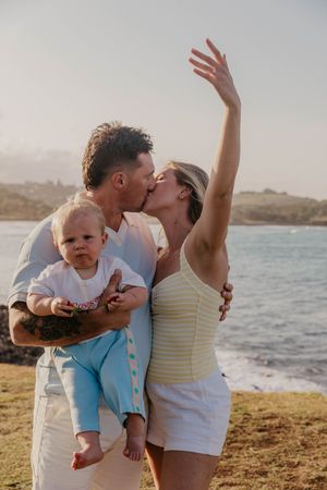 Couple celebrating their engagement with their young child on a Byron Bay beach, photographed by a Byron Bay proposal photographer