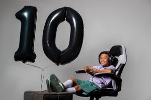 A gaming chair setup with large black number 10 balloons displayed beside it for a milestone celebration.