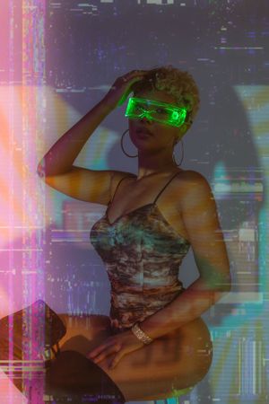 Person in camo bodysuit wearing glowing green LED glasses poses against neon-lit cyberpunk background.