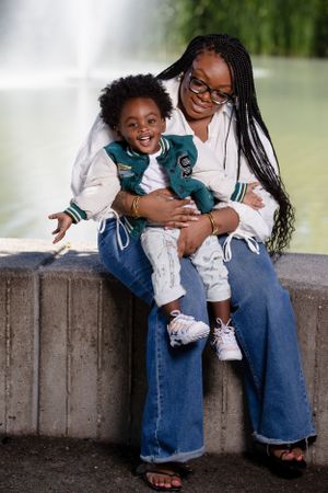 A parent and child share a joyful moment together sitting on a concrete ledge outdoors.