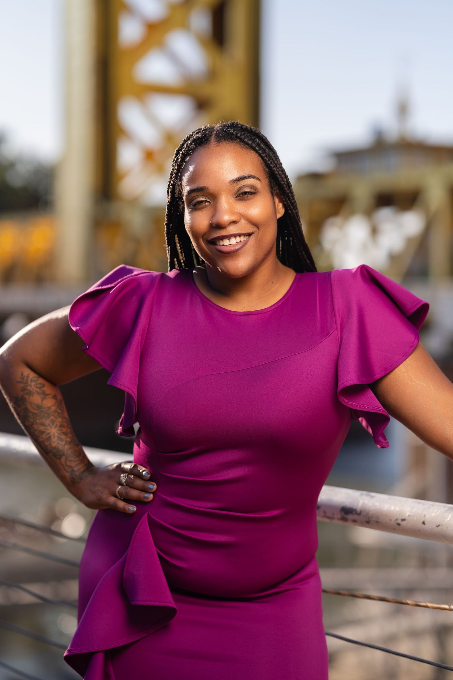 Person wearing a bright magenta ruffle dress poses confidently against an urban backdrop.