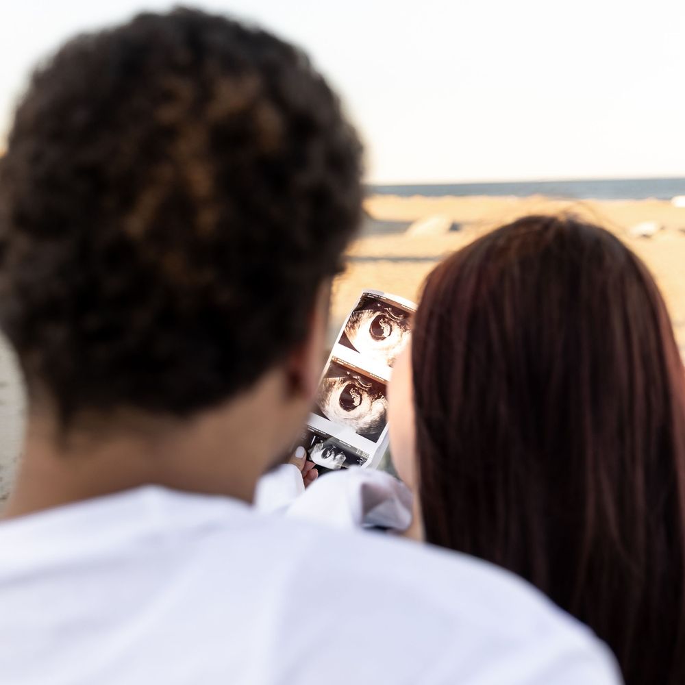 People looking at photo booth style pictures of eyes outdoors with beach and ocean in background.
