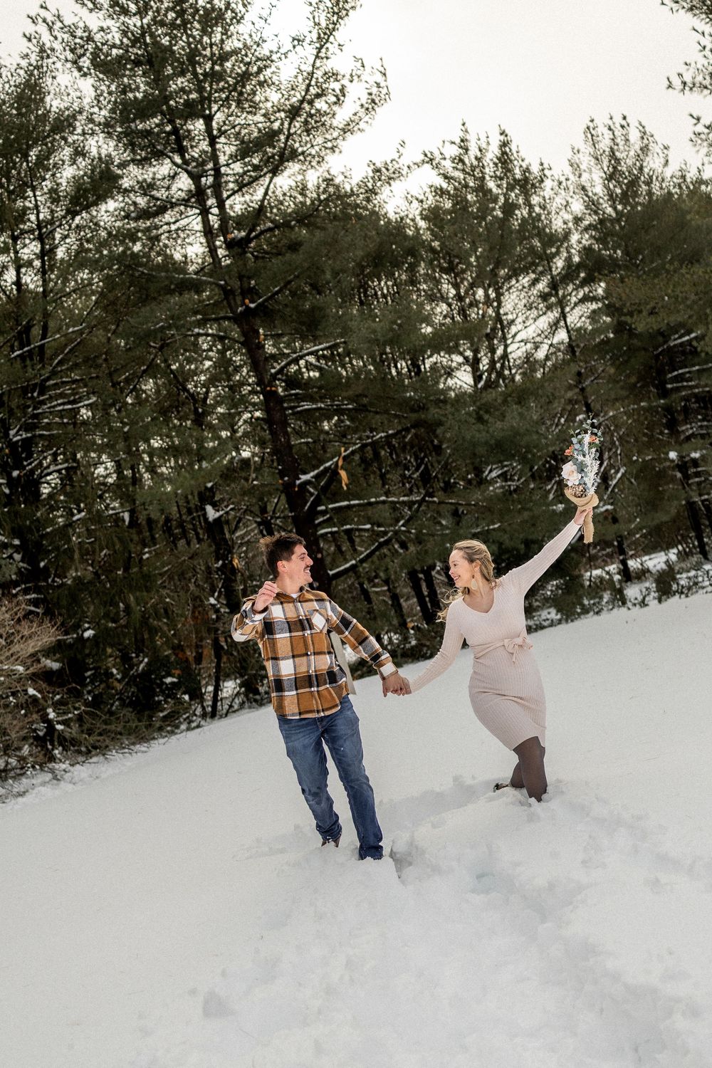Two people playfully throwing snowballs at each other in a snowy forest setting during winter.
