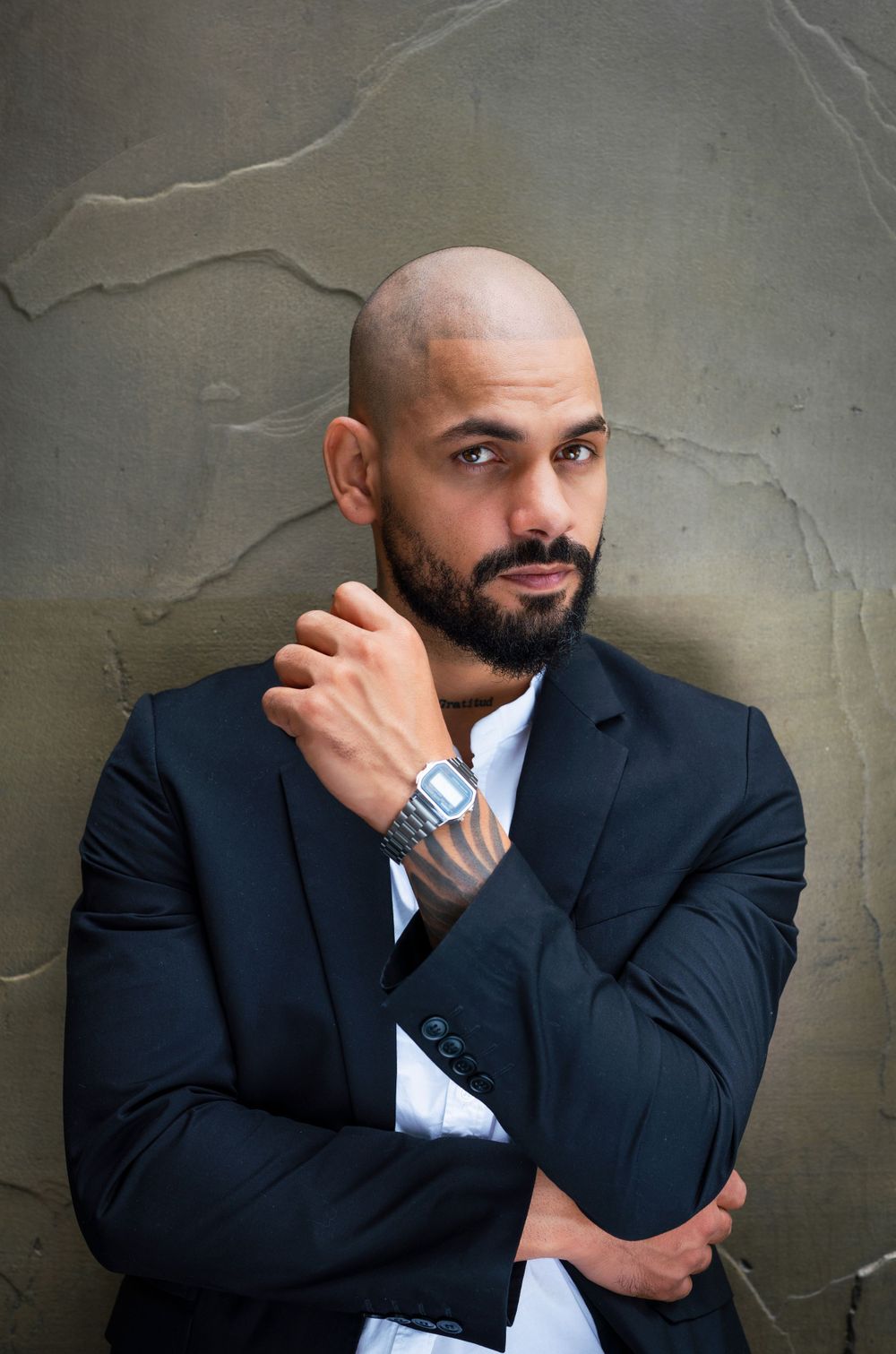 Professional headshot of man in navy suit against textured gray wall.
