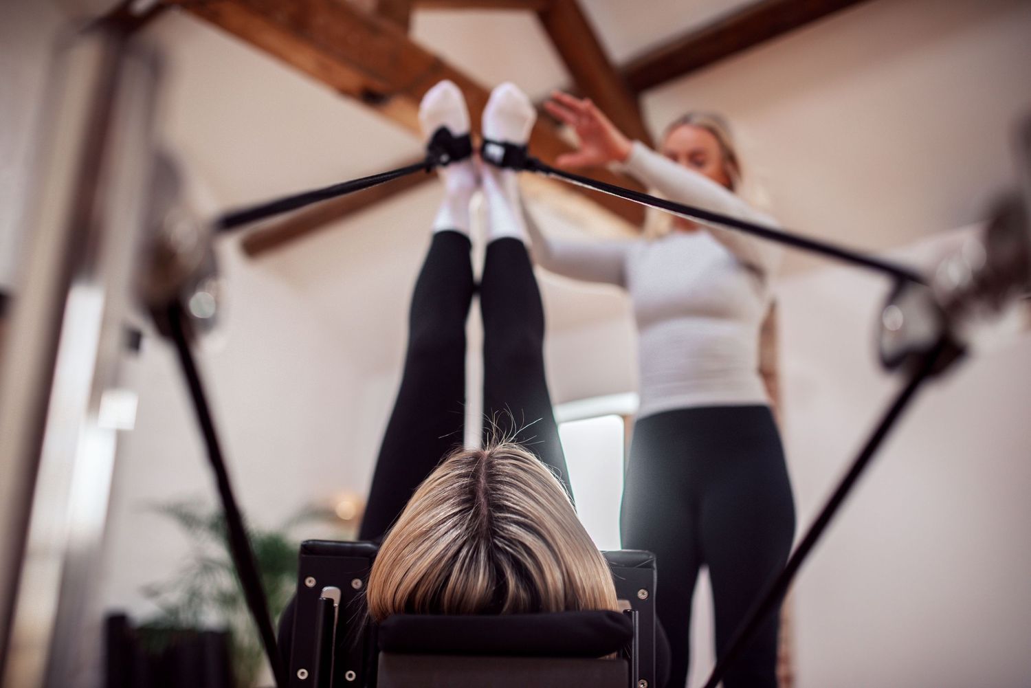 Photo of a pilates instructor with a client using the reformer during a brand photoshoot in Kettering. Hygeia Wellness.