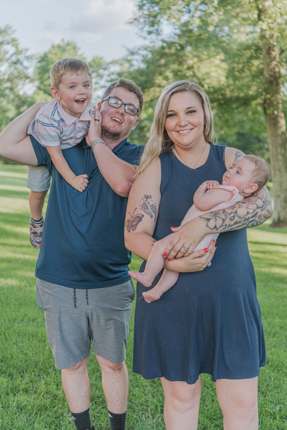 A family stands together on green grass on a sunny day.