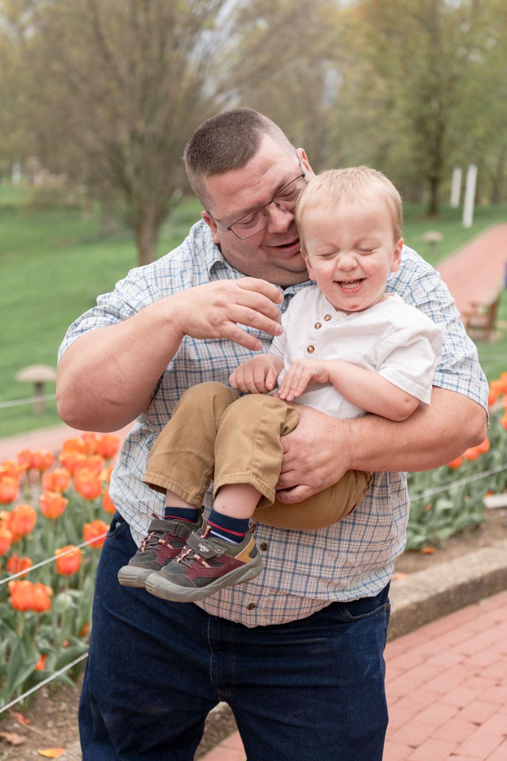 Tender moment between parent and toddler near orange tulip garden.