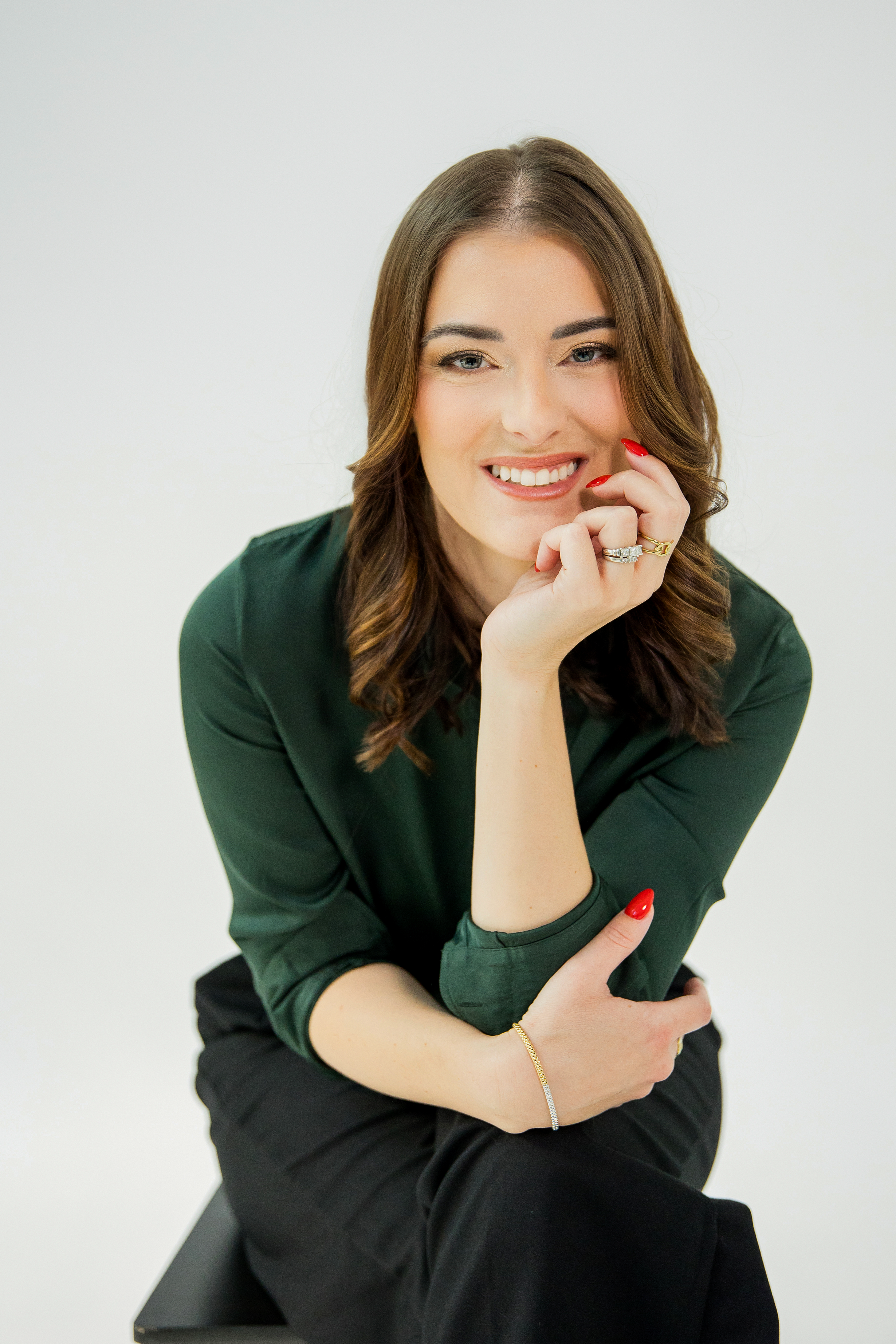 Professional headshot session in dark green top against white background.