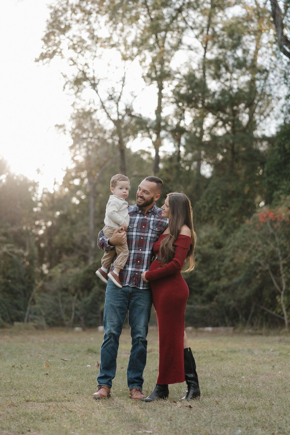 A family shares tender moments together in a sunlit field during an outdoor photo session.