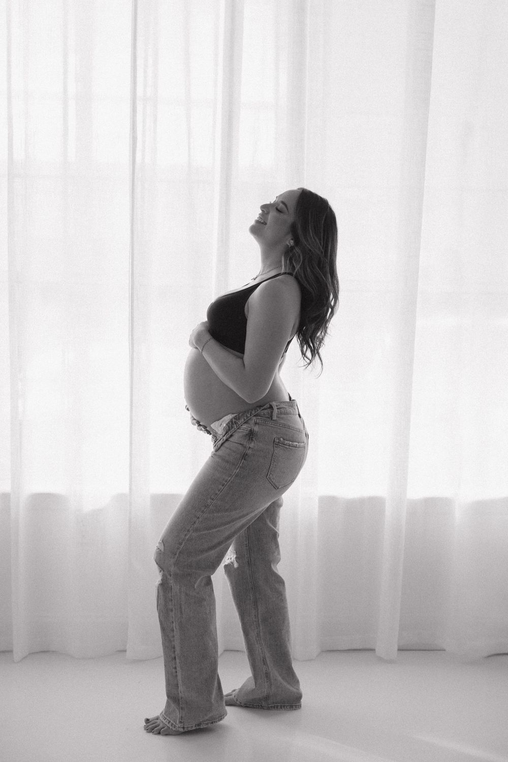 A black and white photo series shows a person in jeans dancing expressively in front of a bright window.