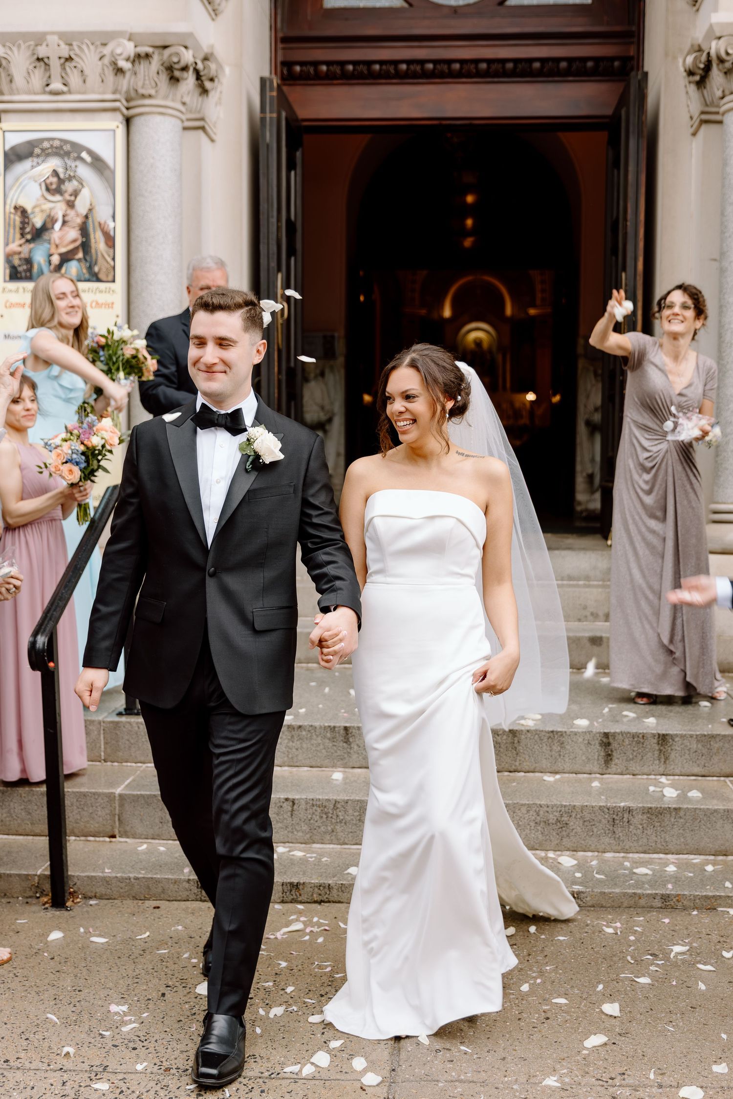 Wedding party celebrating on church steps after ceremony.