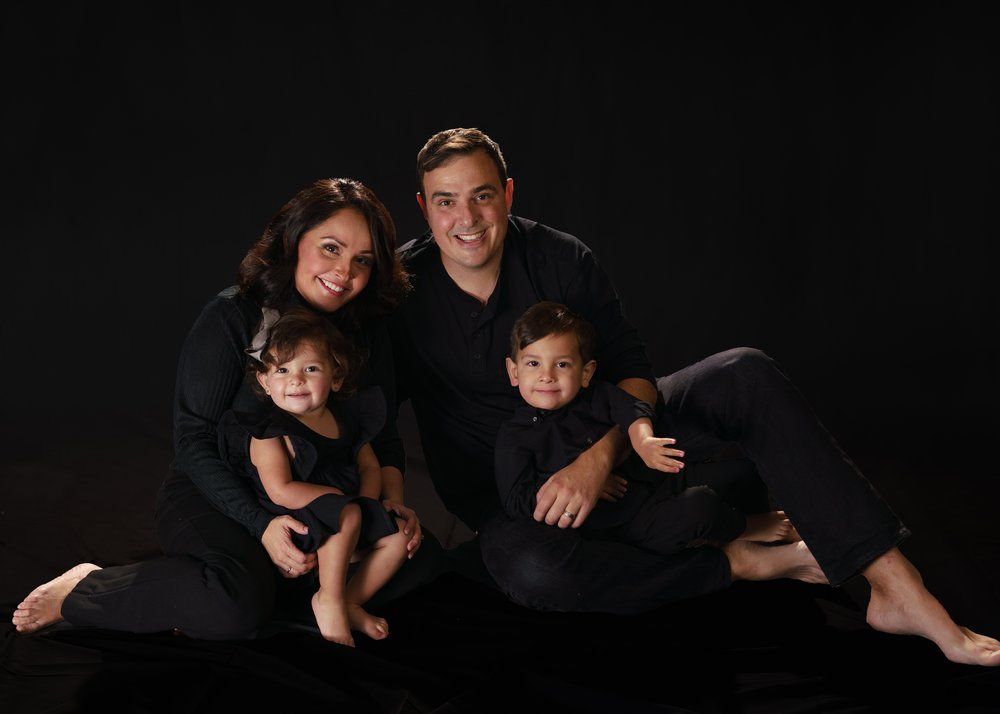 Family of four posing and looking at camera on dark background