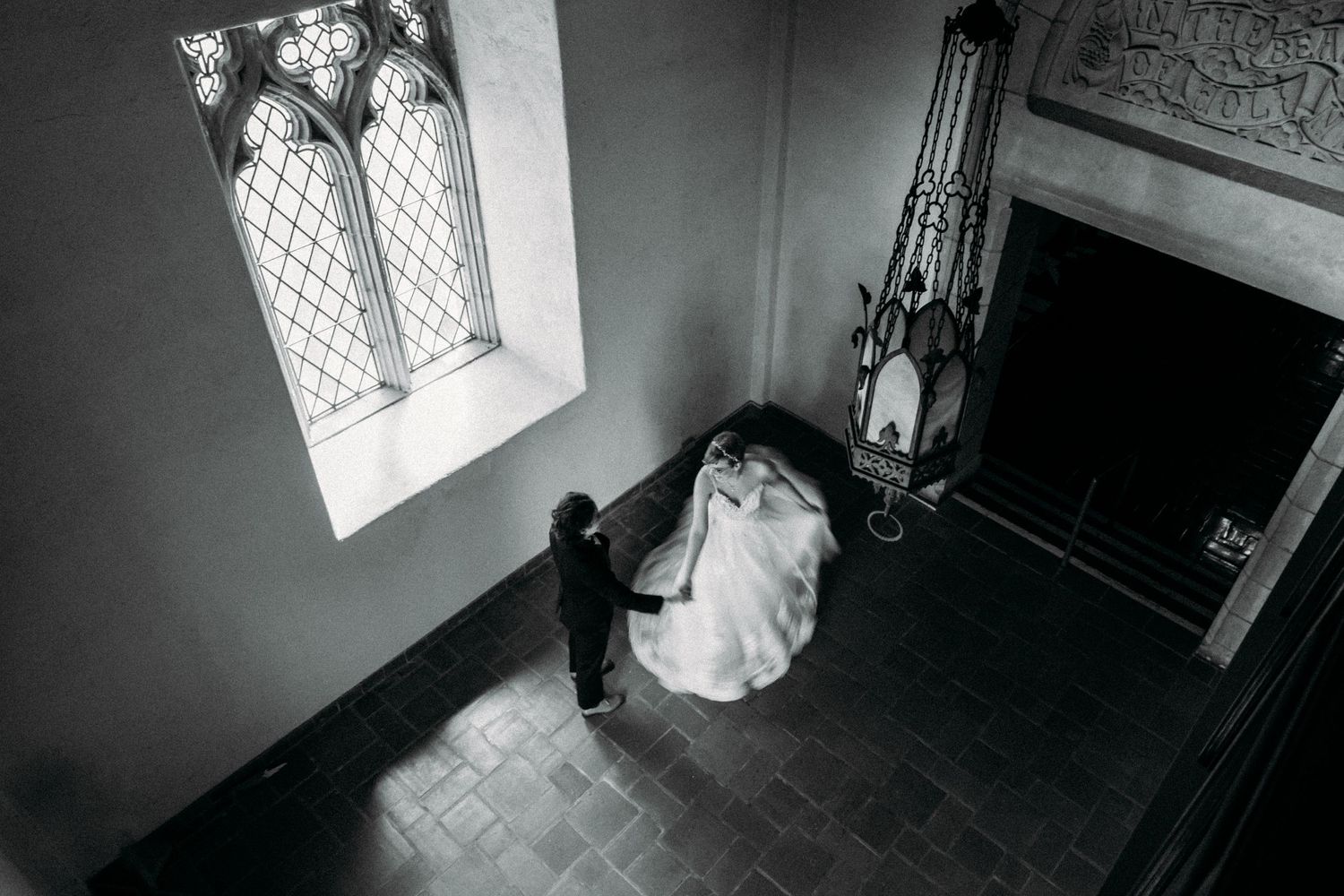 Dramatic overhead wedding photo in gothic chapel with stained glass windows.