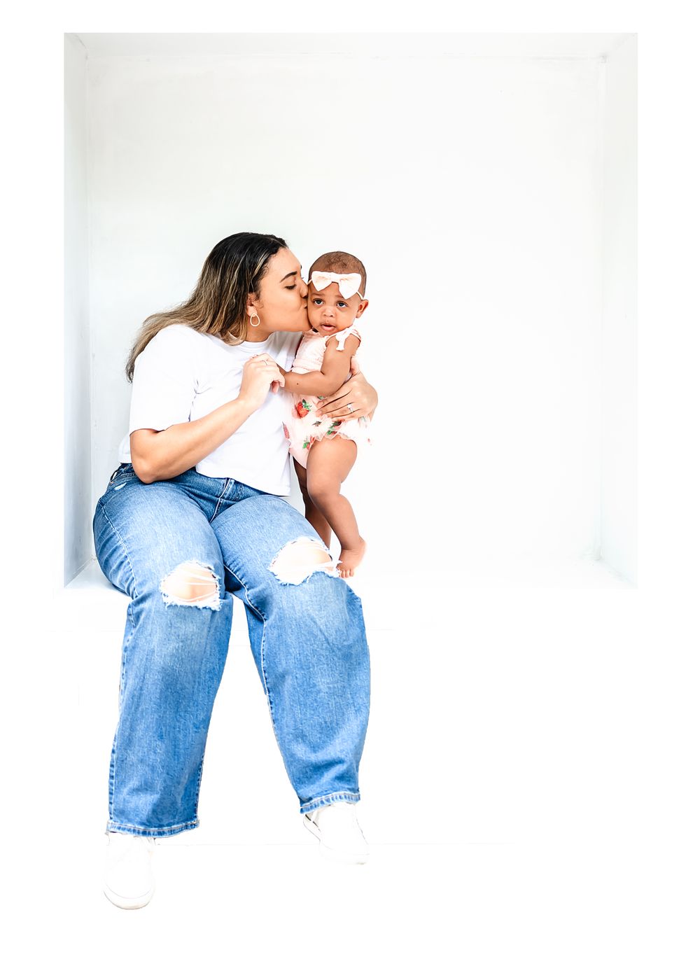 An intimate family portrait against a white background showing maternal affection.