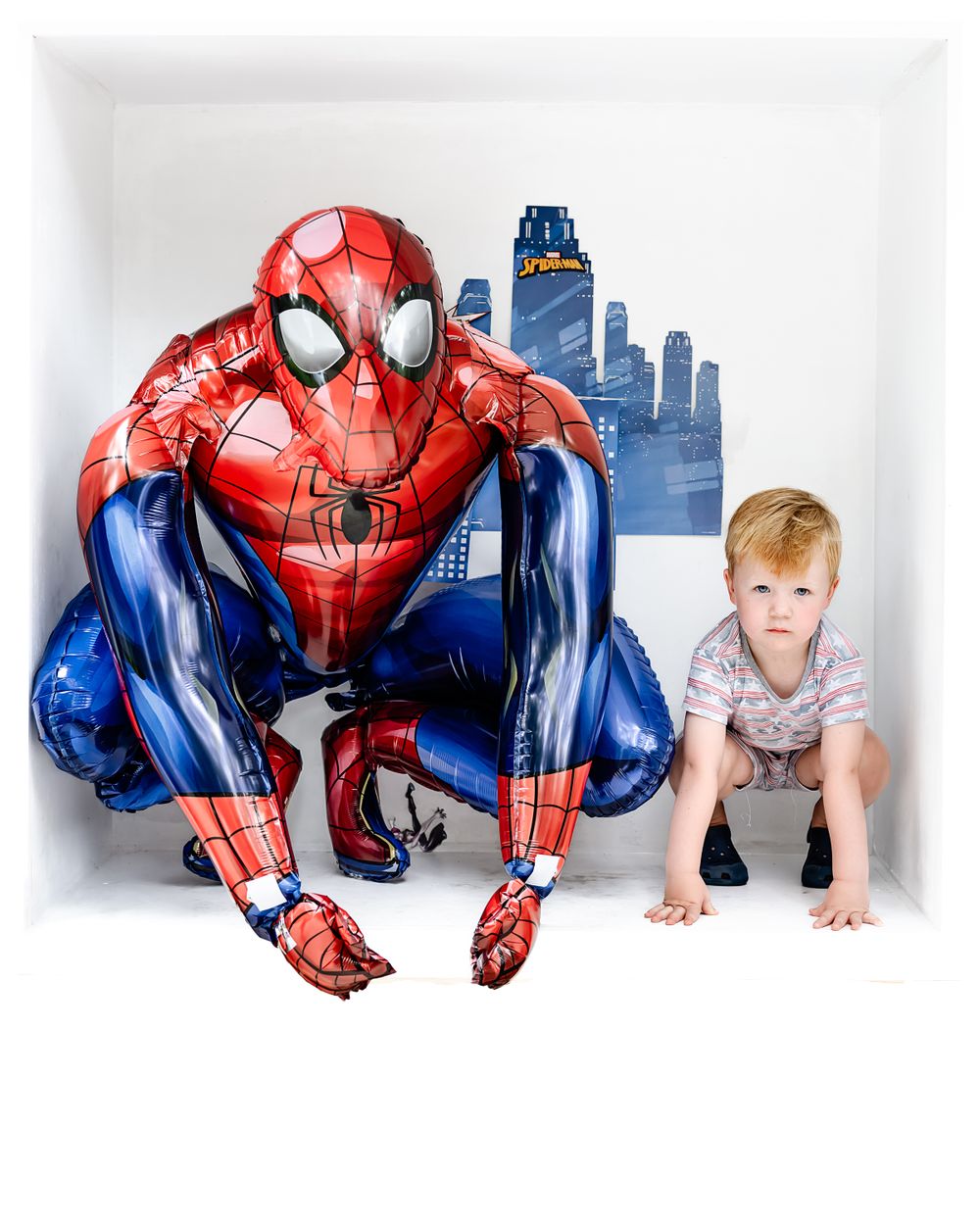 Large Spider-Man balloon figure against a cityscape backdrop for birthday photography.