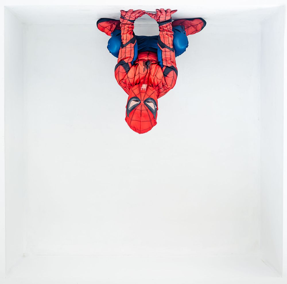 Spider-Man balloon figure hanging upside down against white background.