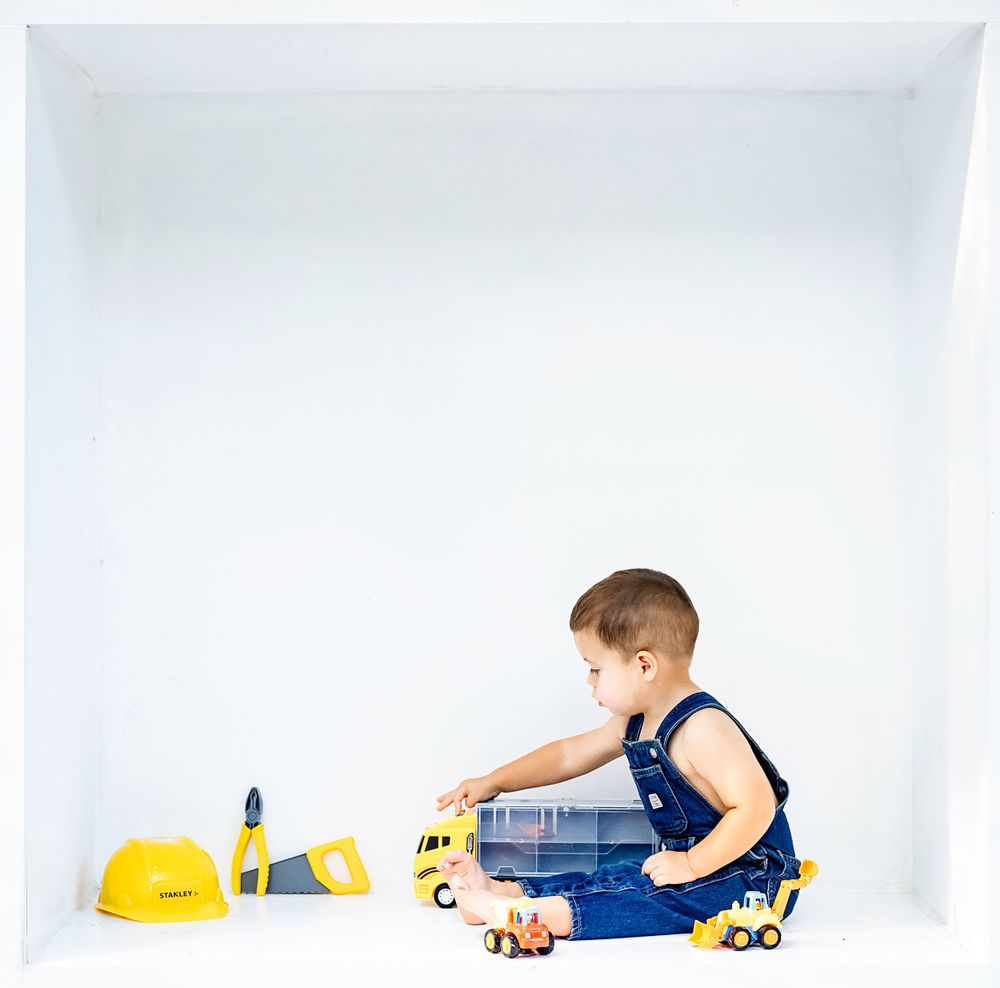 A quiet moment playing with construction toys in a minimalist white photo setting.