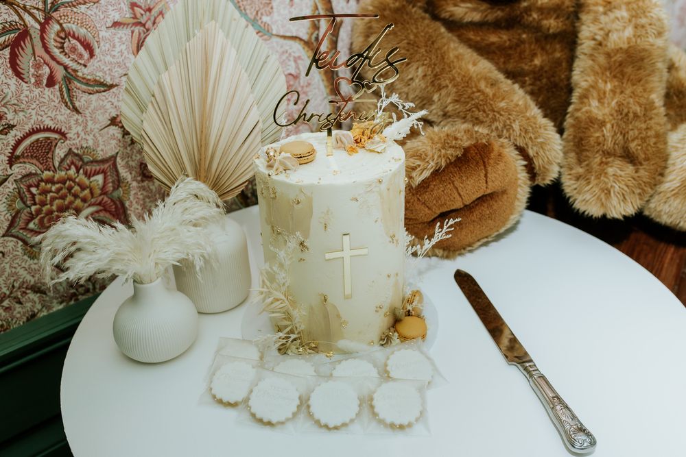 Christening cake with teddy bear and baby name Teddy, elegant baptism cake setup, soft neutral decor, detailed dessert table styling.