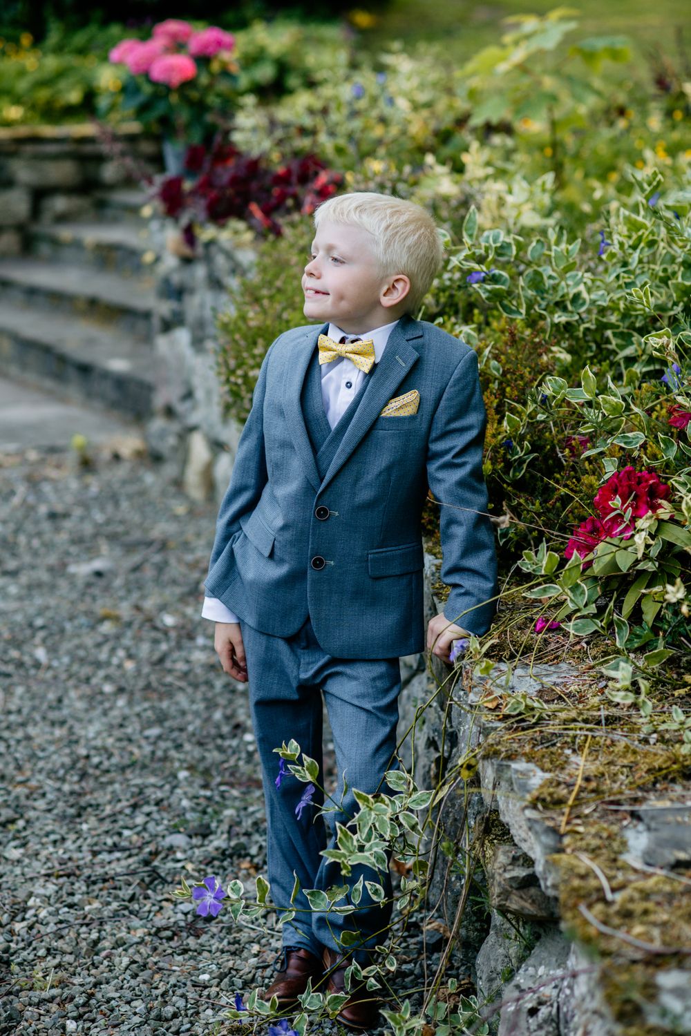 Communion boy standing in a garden setting, outdoor portrait by Ireland family photographer.