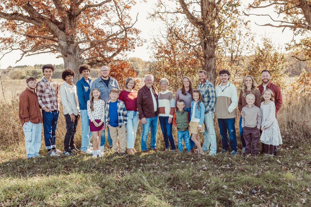 A group gathers outdoors in autumn with golden leaves and sunlight creating a warm, natural backdrop.