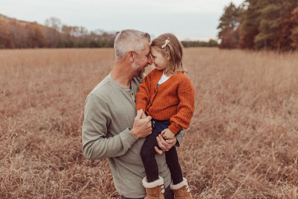 A series of sepia-toned photos showing tender moments between parent and child in an autumn field.