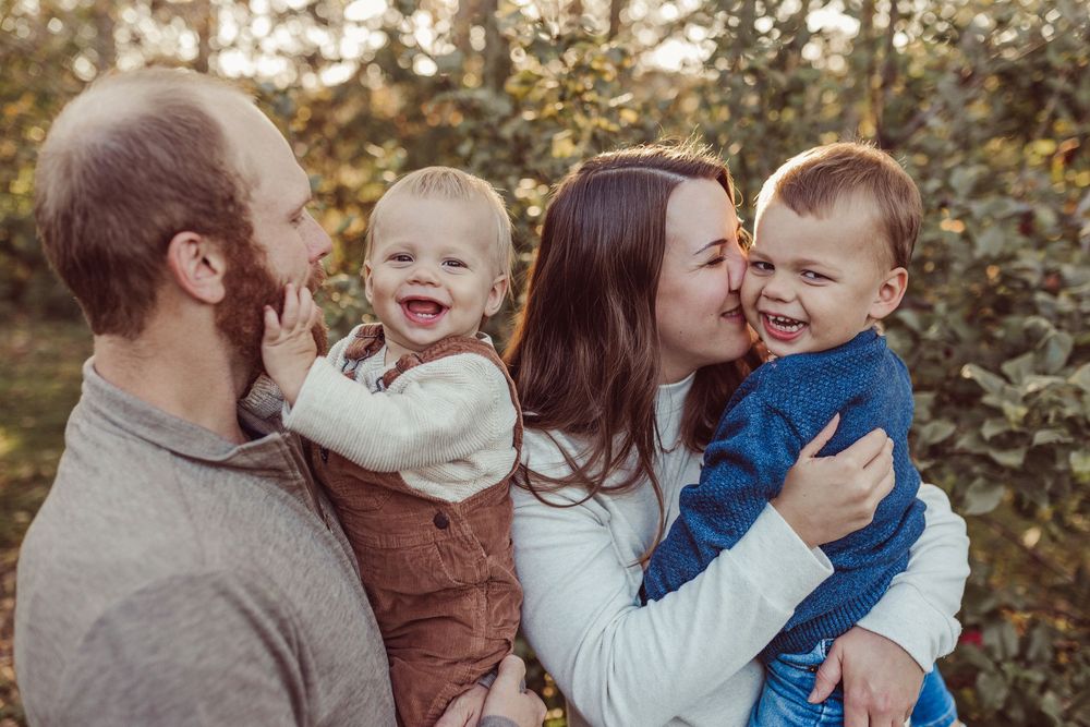 A family shares joyful moments together outdoors during a fall photo session.