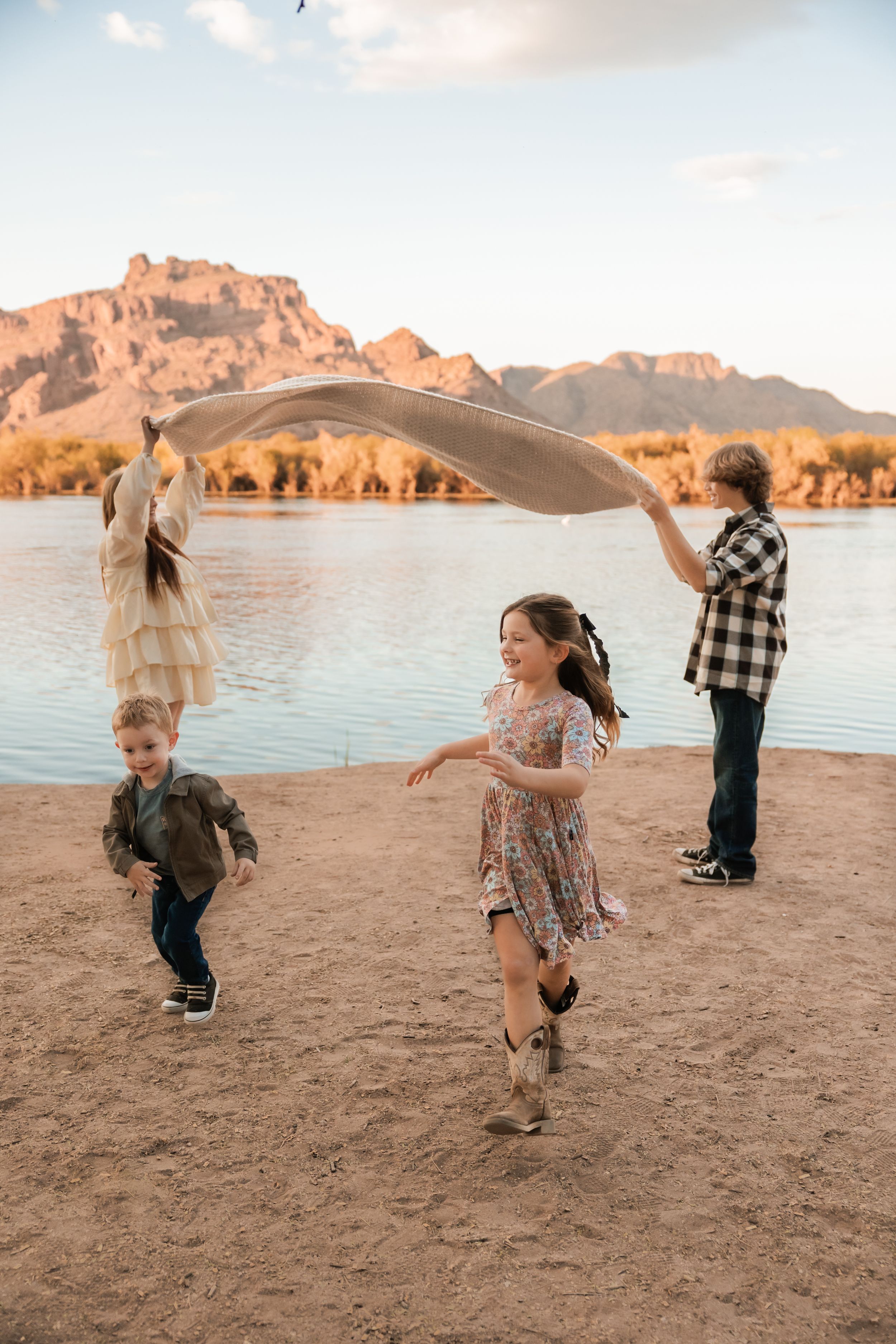 Children run and play together on a sandy beach at sunset with mountains in the background creating joyful moments.