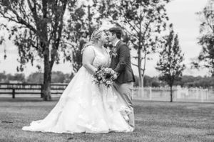 A black and white wedding portrait of a romantic moment in a garden setting.